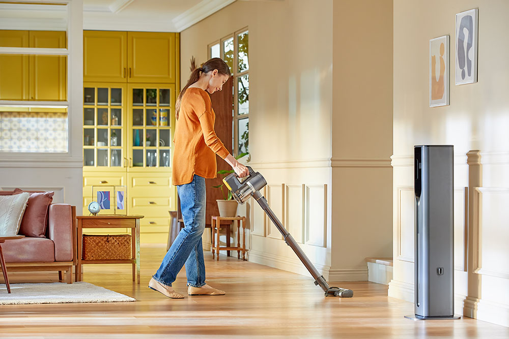 Woman using an LG A9T Ultra Handstick Vacuum cleaner in the lounge