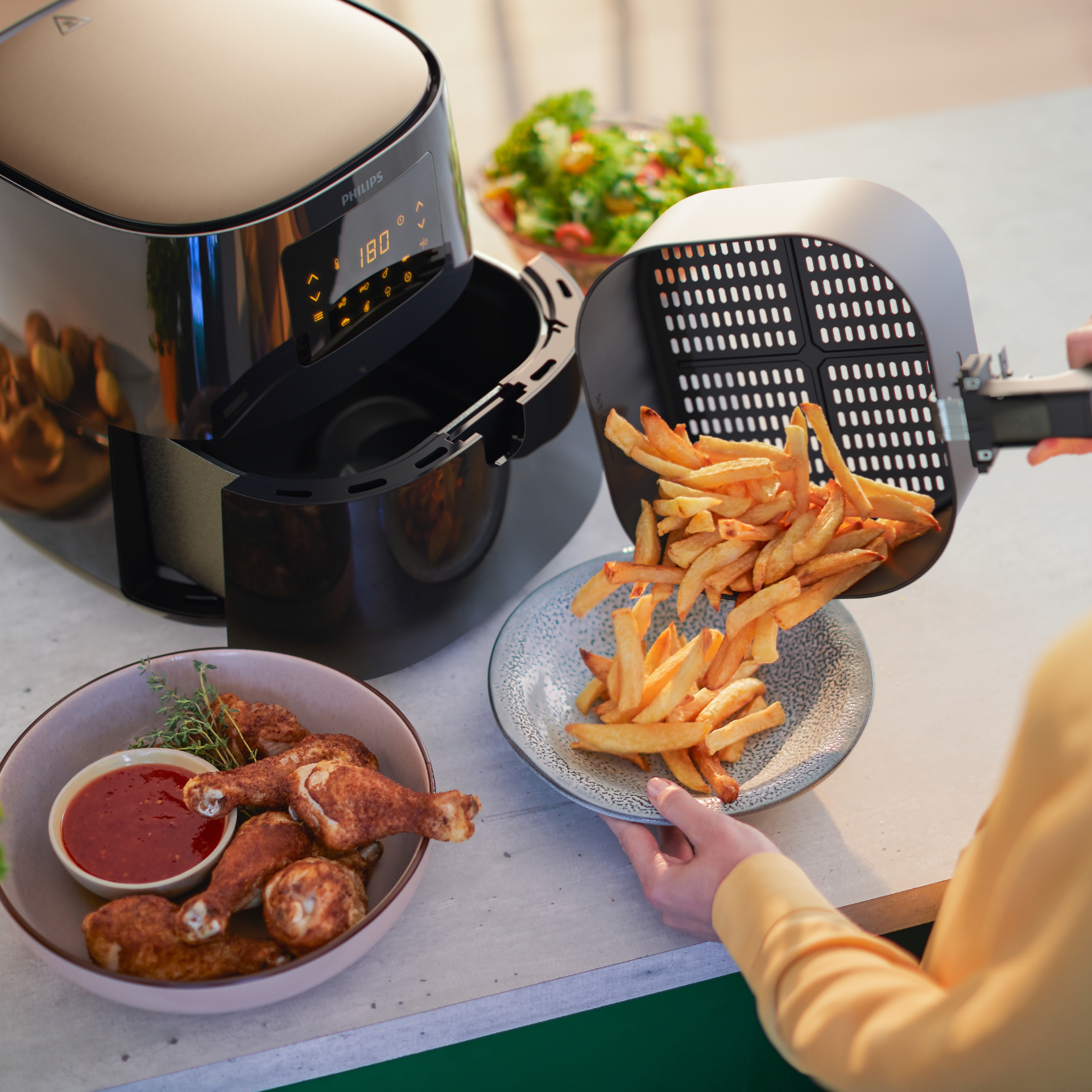 Woman using Philips Essential Airfryer XL to cook fried chicken and chips